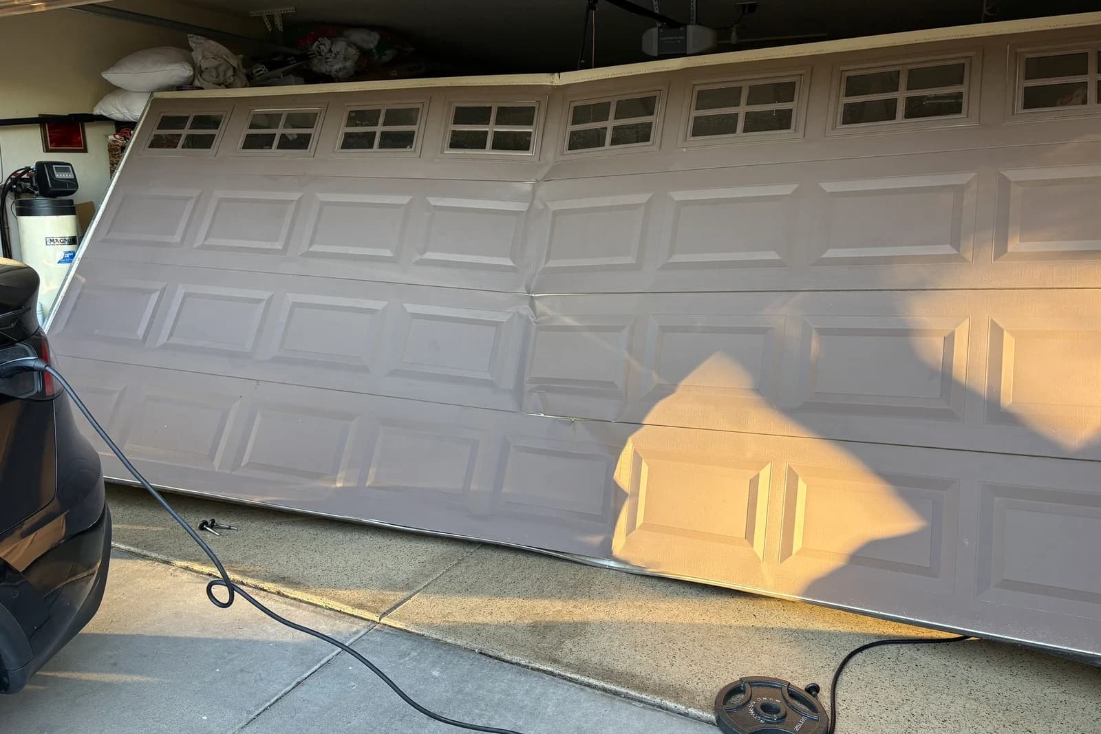 A Phoenix garage door with buckled, damaged panels being assessed for panel replacement by Desert Spring
