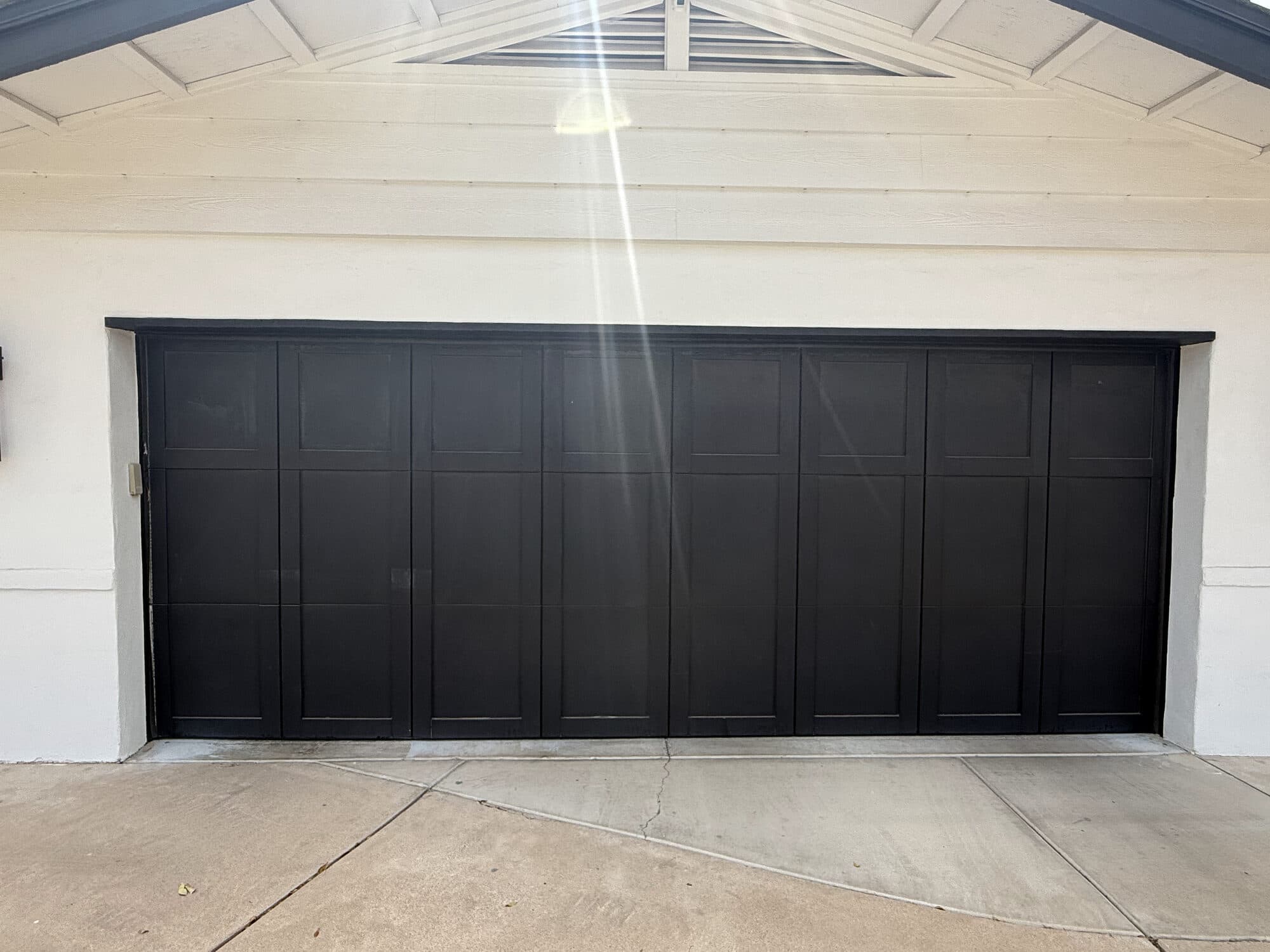 Large black carriage-style garage door straight and level again after an off-track repair by Desert Spring in Phoenix, AZ