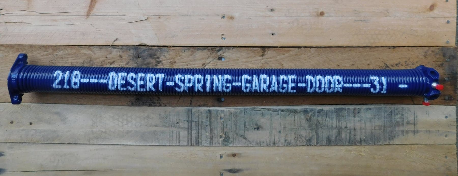 A custom cobalt Desert Spring Performance Spring on wood, showing its coil, winding cones, powder-coated finish and stencil